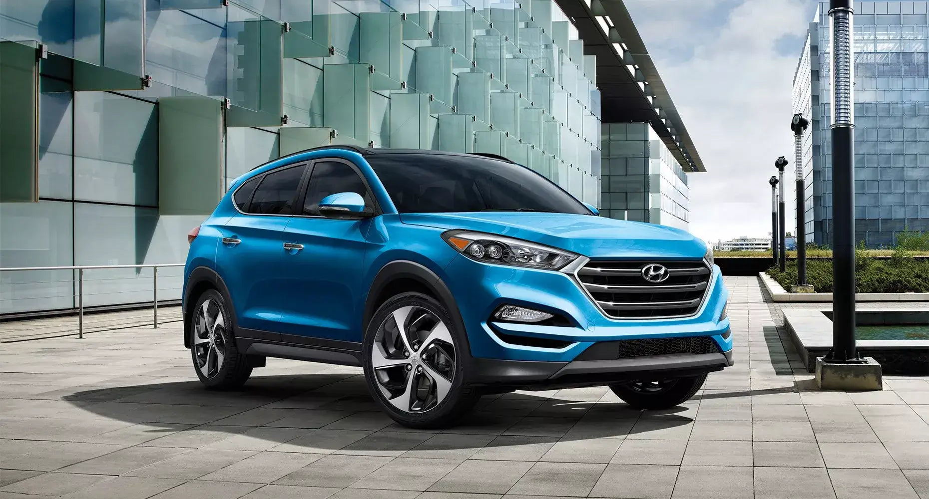 Blue Hyundai Tucson SUV parked in a modern urban setting with glass buildings.