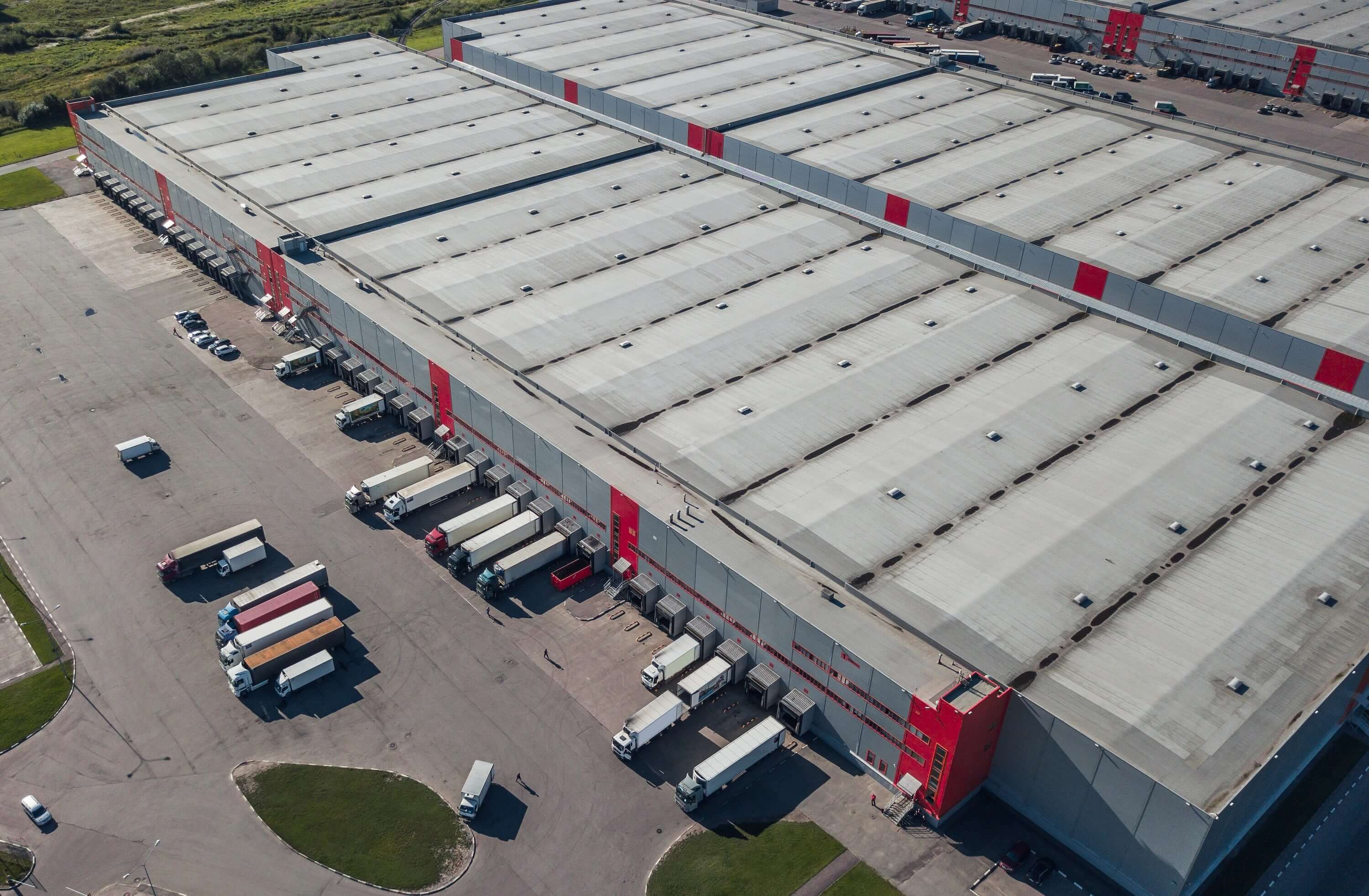 Aerial view of a large warehouse with delivery trucks parked in loading bays, showcasing industrial architecture.