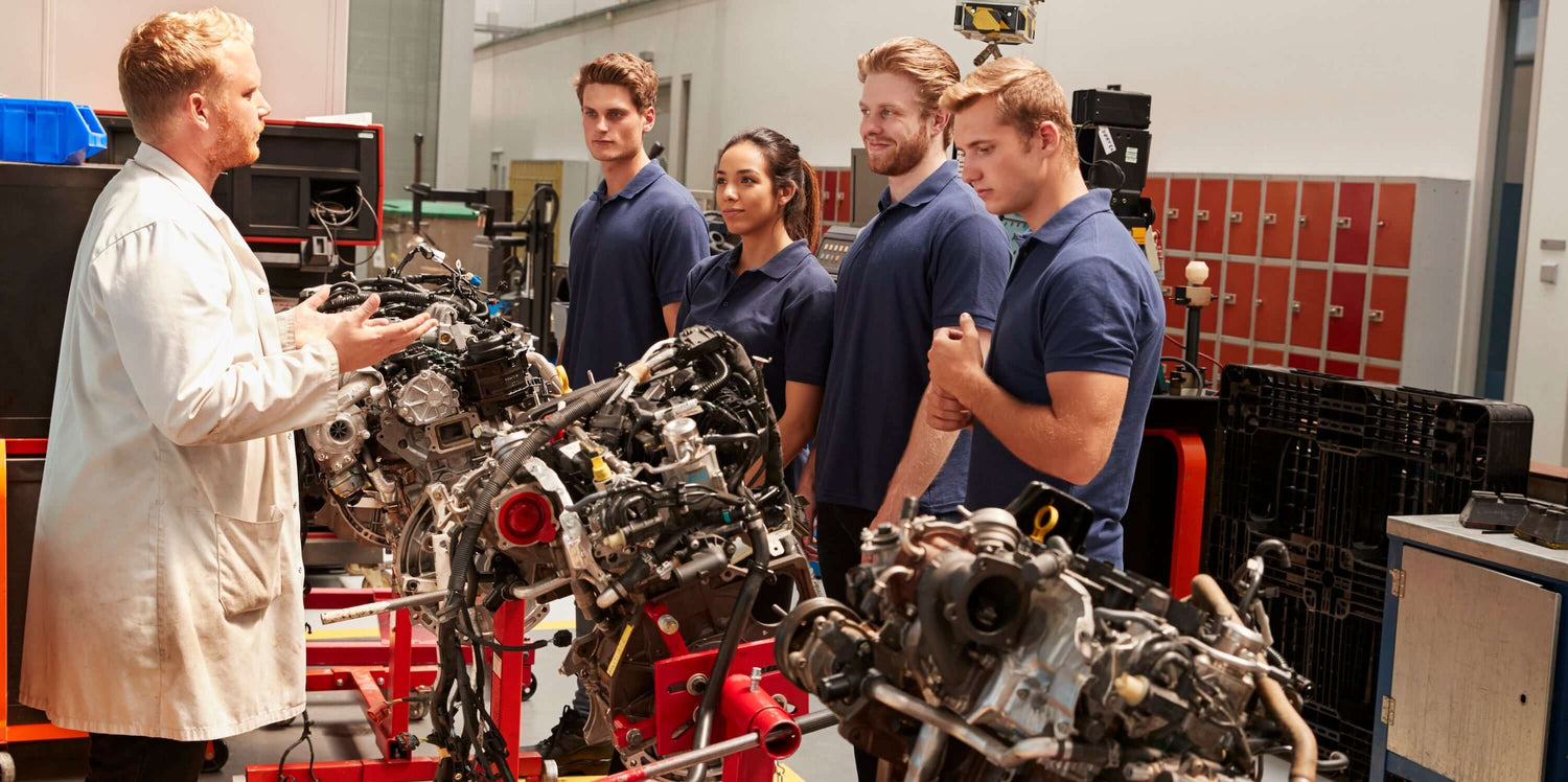 A group of automotive students learning about engine mechanics in a workshop.